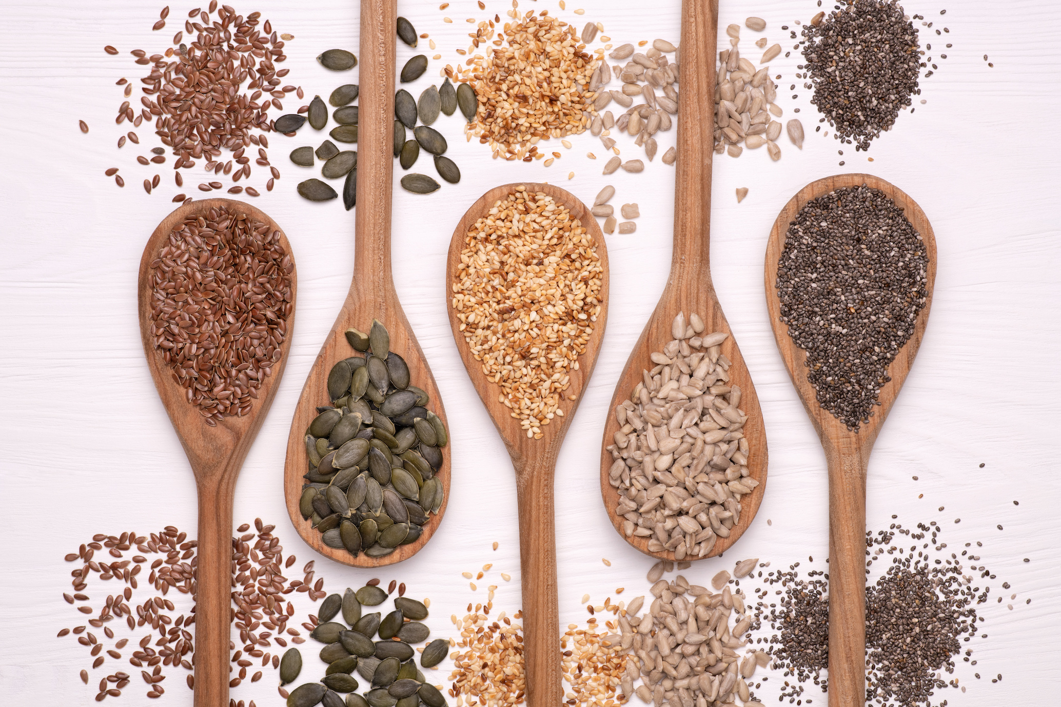 wooden spoons containing different nuts and seeds