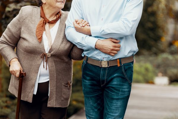 Elder lady holding onto a man's arm