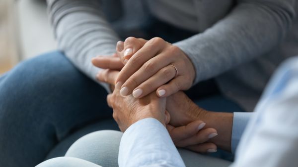 Woman holding hand of man after talking about stroke