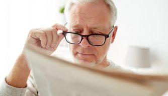 Man with glasses reading newspaper